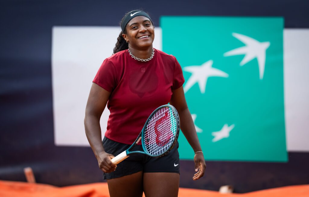 Hailey Baptiste smiles on the tennis court, celebrating her milestone in Paris with support from the Tiafoe family.