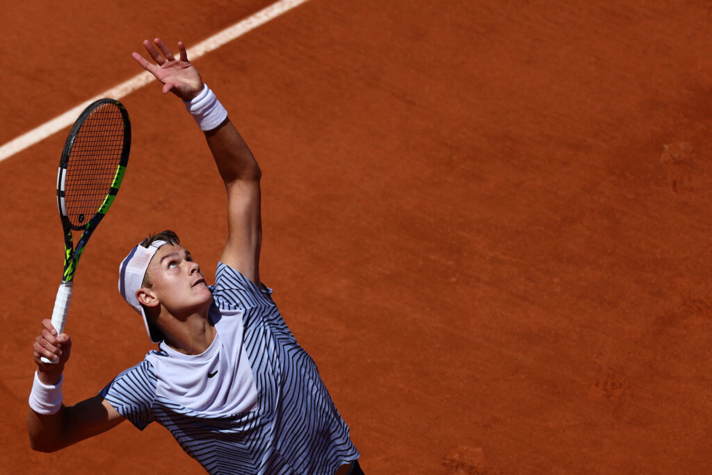 Holger Rune executing a stunning round-the-net winner at the 2025 French Open, showcasing his exceptional skill.