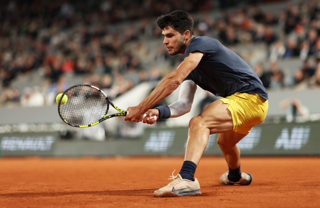 Carlos Alcaraz showcases his aggressive playing style during a tense moment against Damir Dzumhur at the French Open 2025.