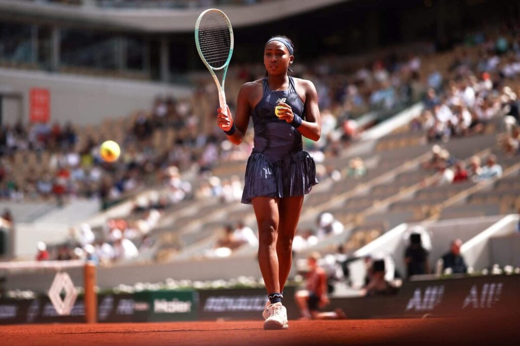Coco Gauff smiles on the court at the French Open, reflecting on her racquet mishap and playful banter with Frances Tiafoe.