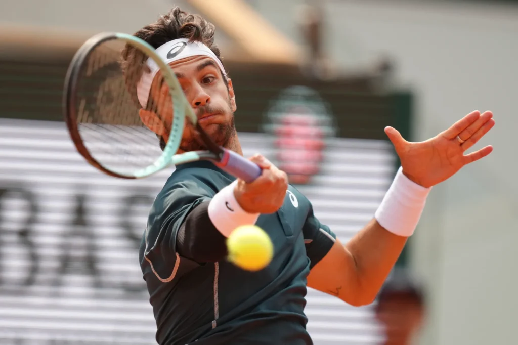 Lorenzo Musetti kicks a ball that strikes a line judge during the French Open quarter-final match against Frances Tiafoe.